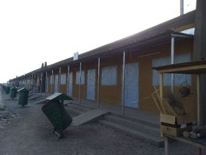 Alignement de boutiques récemment construites à Koupéla, dotées de rampes d’accès et de poubelles métalliques vertes.